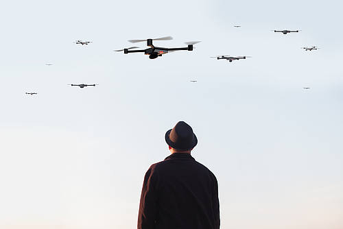 Mann mit Hut betrachtet Drohnen am Himmel