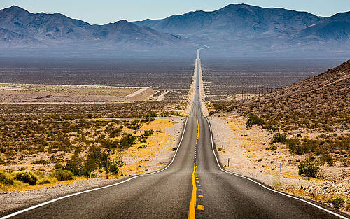Ein langer Highway der durch eine Wüste führt
