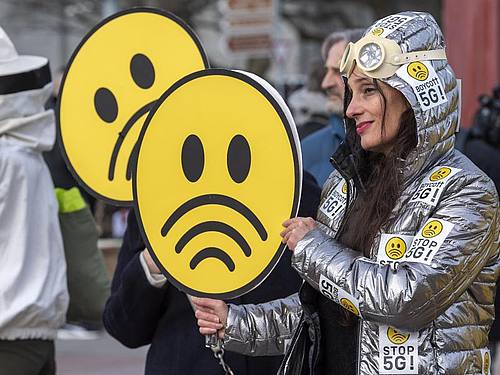 Menschen nehmen an einem weltweiten Protesttag gegen die fünfte Mobilfunkgeneration (5G) mit ultraschnellen Datenverbindungen auf dem Genfer Place des Nations teil. Foto: Martial Trezzini/KEYSTONE/dpa