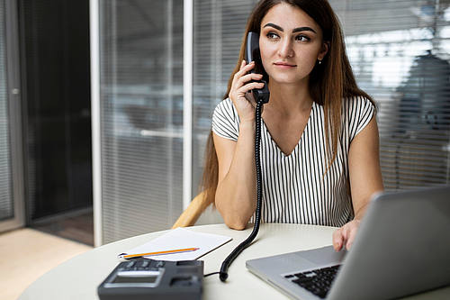 Frau telefoniert über Festnetz im Büro