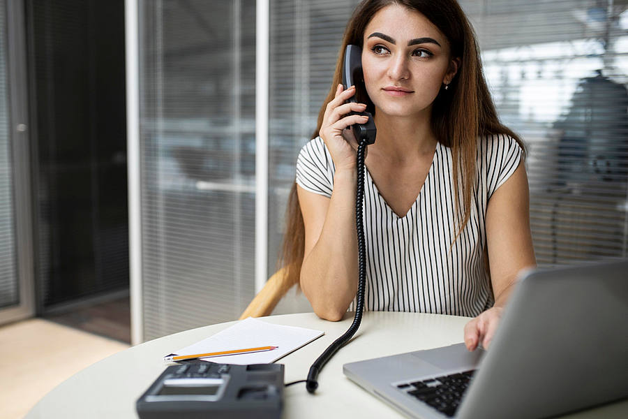 Frau telefoniert über Festnetz im Büro