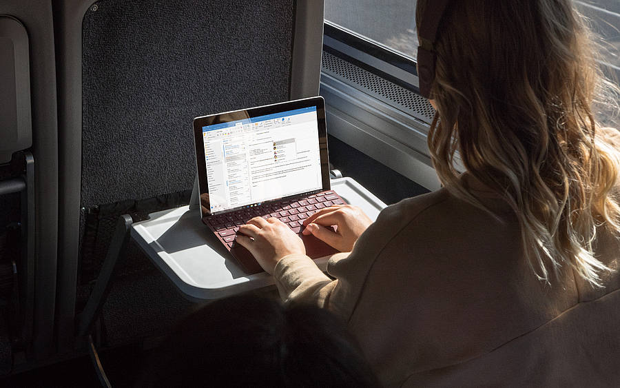 Frau im Zug arbeitet am Laptop