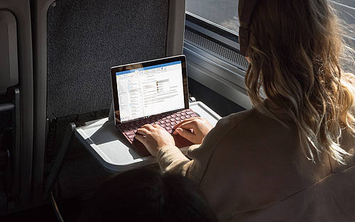 Frau im Zug arbeitet am Laptop