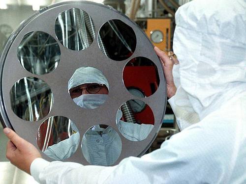 Ein Mitarbeiter der Siltronic AG bei der Herstellung von Siliziumscheiben (Archivfoto). Foto: Matthias Schrader/dpa