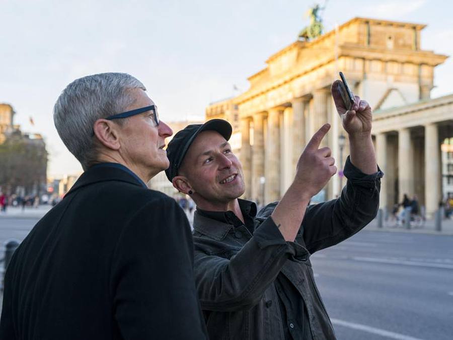 Apple-Chef Tim Cook (l) und Entwickler Peter Kolski schauen auf Smartphone-App. Foto: Brooks Kraft/Apple/dpa