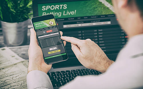 Mann mit Handy bei Sportwette