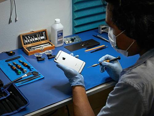 Ein Service-Techniker arbeitet an einem iPhone. Foto: Apple/dpa