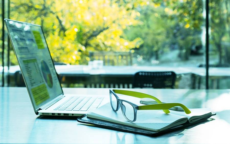 Person arbeitet mit Notebook vor sonnigem Fenster