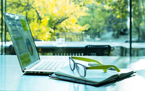 Person arbeitet mit Notebook vor sonnigem Fenster