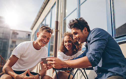 Drei Leute schauen auf Smartphone