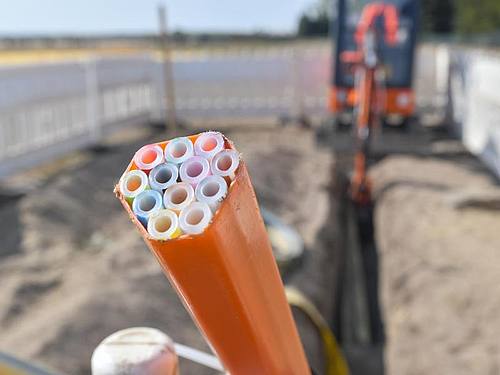 Farbige Leerrohre, in die später die Glasfaserkabel verlegt werden, ragen aus einem Graben auf einer Baustelle im brandeburgischen Grassau. Foto: Patrick Pleul