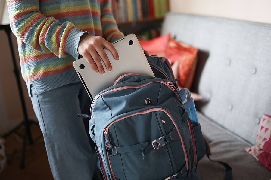Junge Person mit Laptop und Rucksack