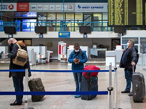 Passagiere mit Smartphones in einer Schlange im Internationalen Flughafen von Vilnius. Foto: Mindaugas Kulbis/AP/dpa