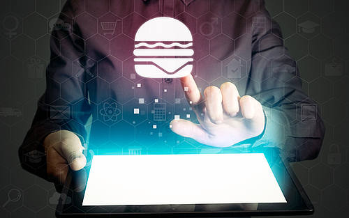 Ein Mann wählt auf einem Tablet einen Burger aus