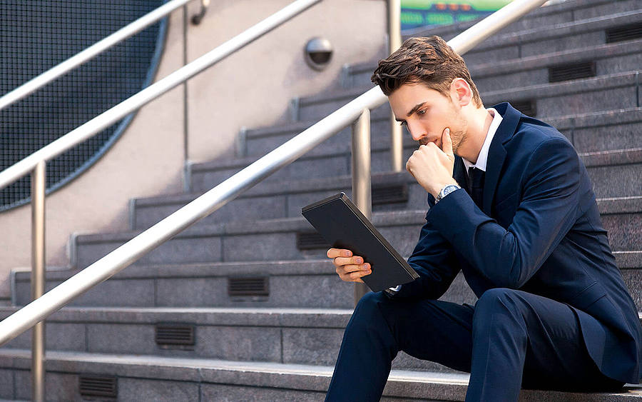 Ein Geschäftsmann sitzt mit einem Tablet auf einer Treppe