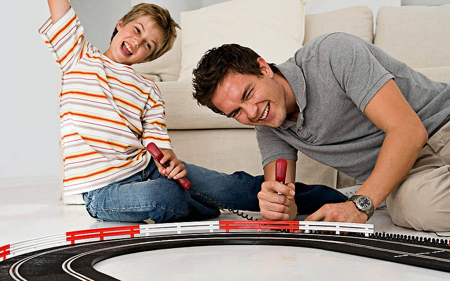 Vater und Sohn spielen mit Carrera-Bahn